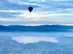 Opinie lot balonem beskid wyspowy - balon na ogrzane powietrze, w tle góry, w dole miasto Dobczyce i zalew dobczycki